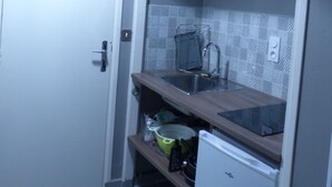 Una cocina compacta con un refrigerador blanco, un lavamanos y una lámpara colgante.