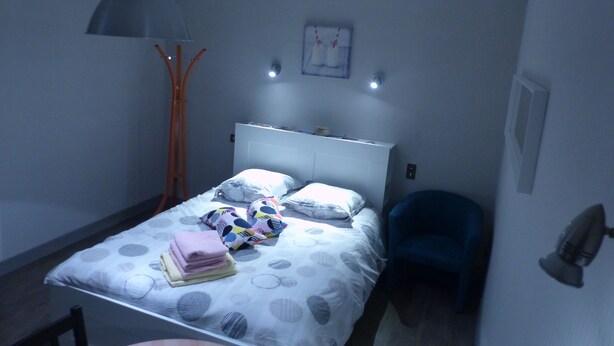 Un dormitorio pequeño y ordenado con cama, mesita de noche y una silla.