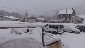 Un barrio residencial cubierto de nieve, con casas y vehículos estacionados.