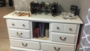 Een witte dressoir met lades en een wijnrek erboven.