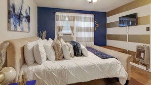 Une chambre à coucher avec un lit, un ventilateur de plafond, une télévision et un radiateur.