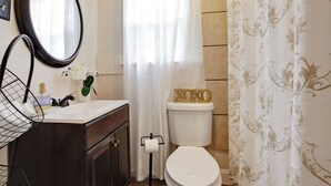 Une salle de bain comprenant des toilettes, un lavabo avec un miroir, un rideau de douche et un porte-serviettes.