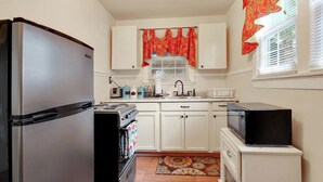 Une cuisine compacte équipée d’un réfrigérateur, d’une cuisinière, d’un four à micro-ondes et d’un petit placard.
