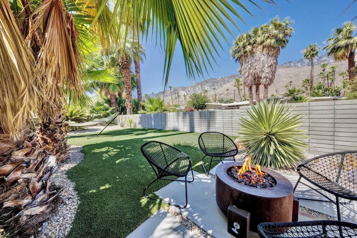 Un espacio al aire libre con césped artificial, una chimenea y sillas para exteriores.