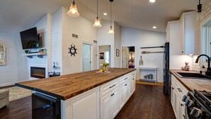 A modern kitchen with a wooden island, white cabinetry, and pendant lighting. - Blue Fish Cottage-Hot tub, Kayaks, Ice Fishing (Waterford)