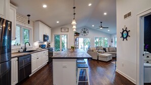 A spacious kitchen with white cabinets, a central island with stools, and a large island sink. - Blue Fish Cottage-Hot tub, Kayaks, Ice Fishing (Waterford)