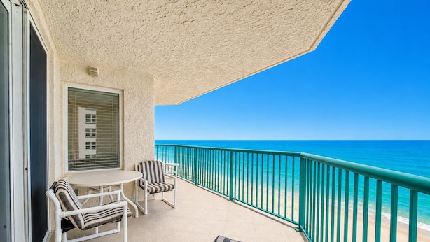 A balcony with a table and chairs, a window with blinds, and a view of the ocean. - Oceanfront | Heated Pool-Towers Grande #508 (Daytona Beach Shores)