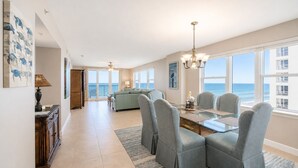 A spacious living area with a dining table, chairs, and a view of the ocean. - Oceanfront | Heated Pool-Towers Grande #508 (Daytona Beach Shores)