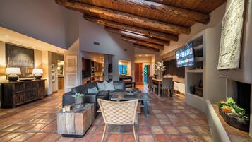 A spacious living room with a large sectional sofa, a coffee table, and a TV mounted on the wall.