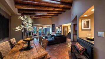 A spacious living area with a wooden dining table, wicker chairs, a sofa, and a fireplace.