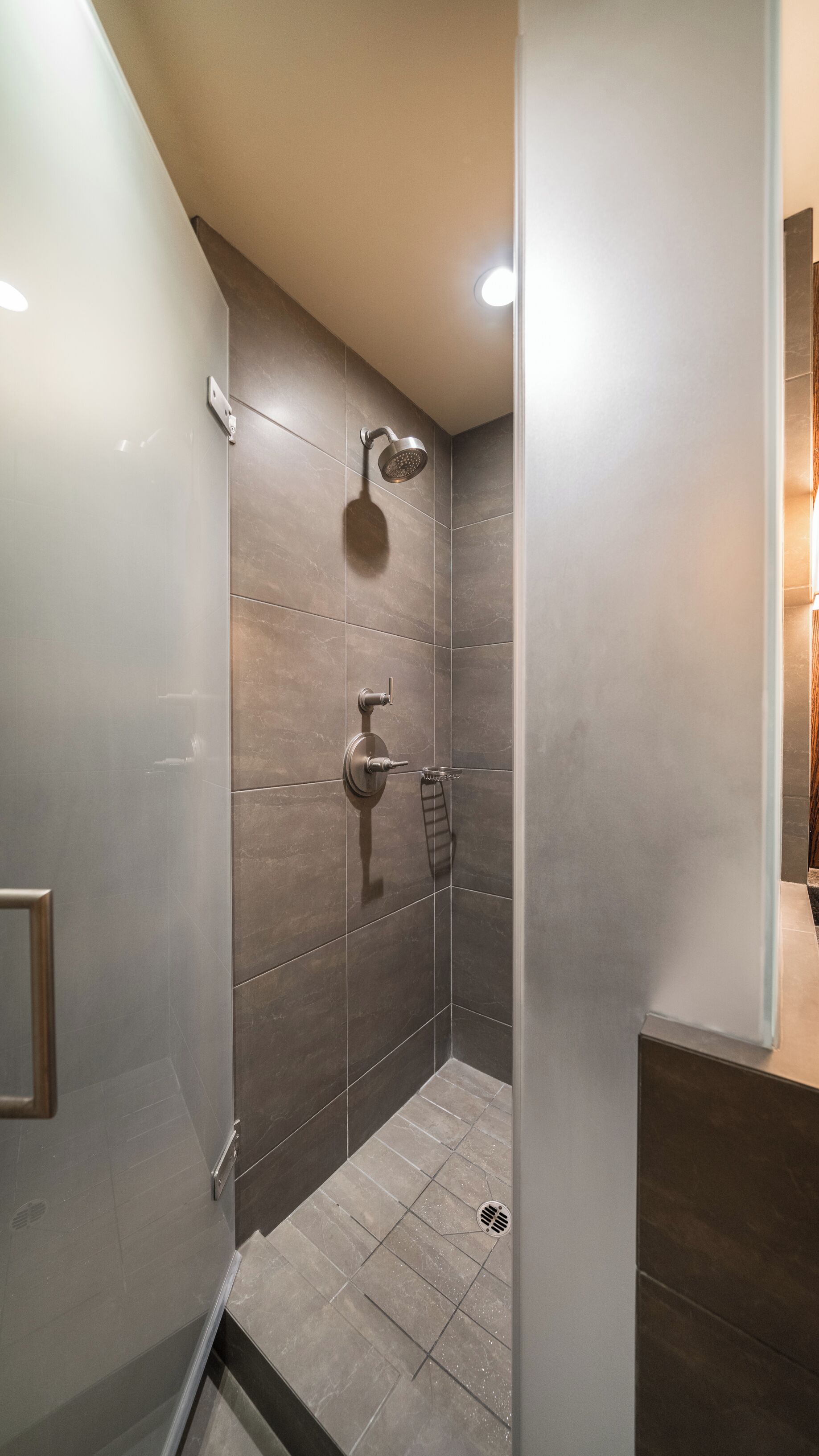 A modern shower with a handheld showerhead and a wall-mounted faucet.