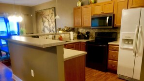 A kitchen with wooden cabinets, a microwave, a refrigerator, and a central island. - Exquisite 2BR Luxurious Suite Great location in Greenville (Greenville)