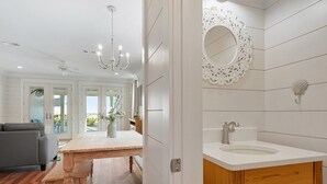 Een moderne badkamer met een wit wastafel, houten kastje en decoratieve spiegel.