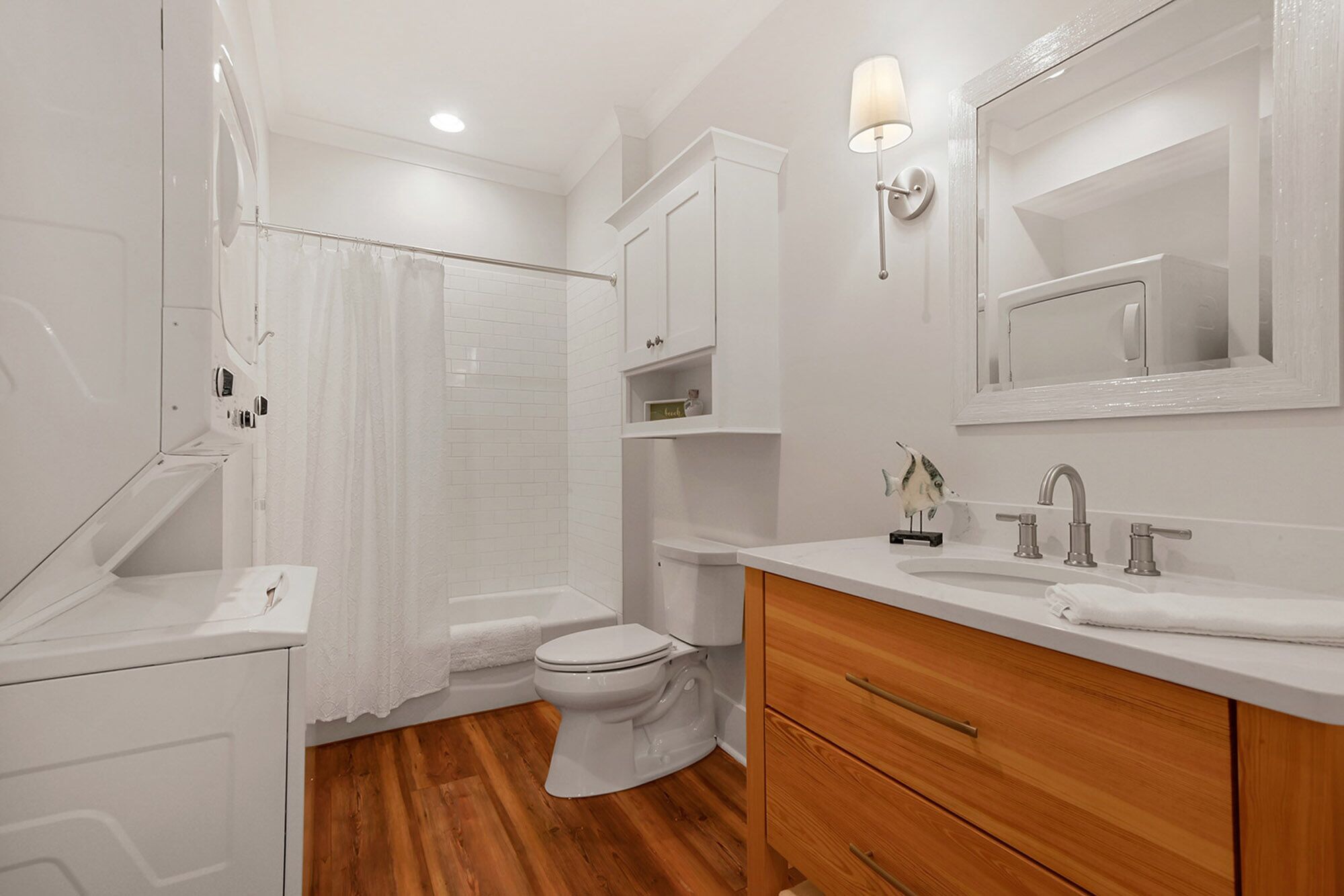 Een moderne badkamer met douche, toilet, wastafel en spiegel.