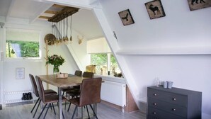 Ein Essbereich mit einem Holztisch, braunen Stühlen und einer dunklen Kommode.