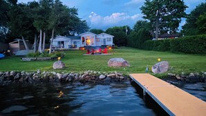 A lakeside property with a dock, a house with a fire pit, and a well-maintained lawn.