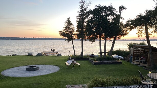 A well-maintained outdoor patio area with a circular seating arrangement, a fire pit, and a view of the water.