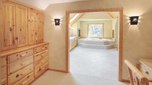 Une salle de bain spacieuse avec une grande baignoire, des meubles en bois et une vue sur l’extérieur par une fenêtre.