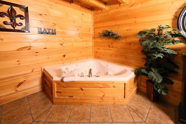 A wooden cabin bathroom with a bathtub, a wooden bench, and a potted plant.