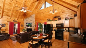 A spacious living room with a wooden ceiling, a dining area with a wooden table and chairs, and a kitchen with wooden cabinets and appliances. - #1  (AMAZING GATED COMMUNITY) - YOUR OWN PRIVATE (SAUNA & HOTTUB) ON BACK DECK (Sevierville)