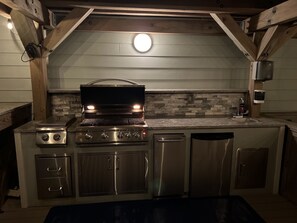 Una cocina moderna con una parrilla integrada, electrodomésticos de acero inoxidable y un salpicadero de piedra.