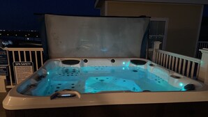 A hot tub with a transparent cover, a safety sign, and a view of the surrounding area. - Waterfront Lux Private hot tub & elevator, marina (Port Aransas)