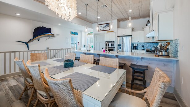 A modern kitchen with white cabinets, a central island, and a hanging light fixture. - Waterfront Lux Private hot tub & elevator, marina (Port Aransas)