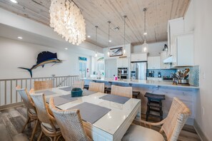 A modern kitchen with white cabinets, stainless steel appliances, and a blue backsplash. - Waterfront Private Spa & elevator, Early Checkink (Port Aransas)