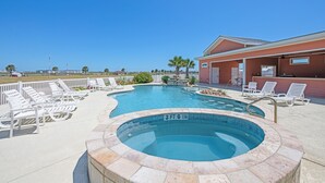 A swimming pool with lounge chairs, a hot tub, and a building with a red exterior. - Waterfront Lux Private hot tub & elevator, marina (Port Aransas)