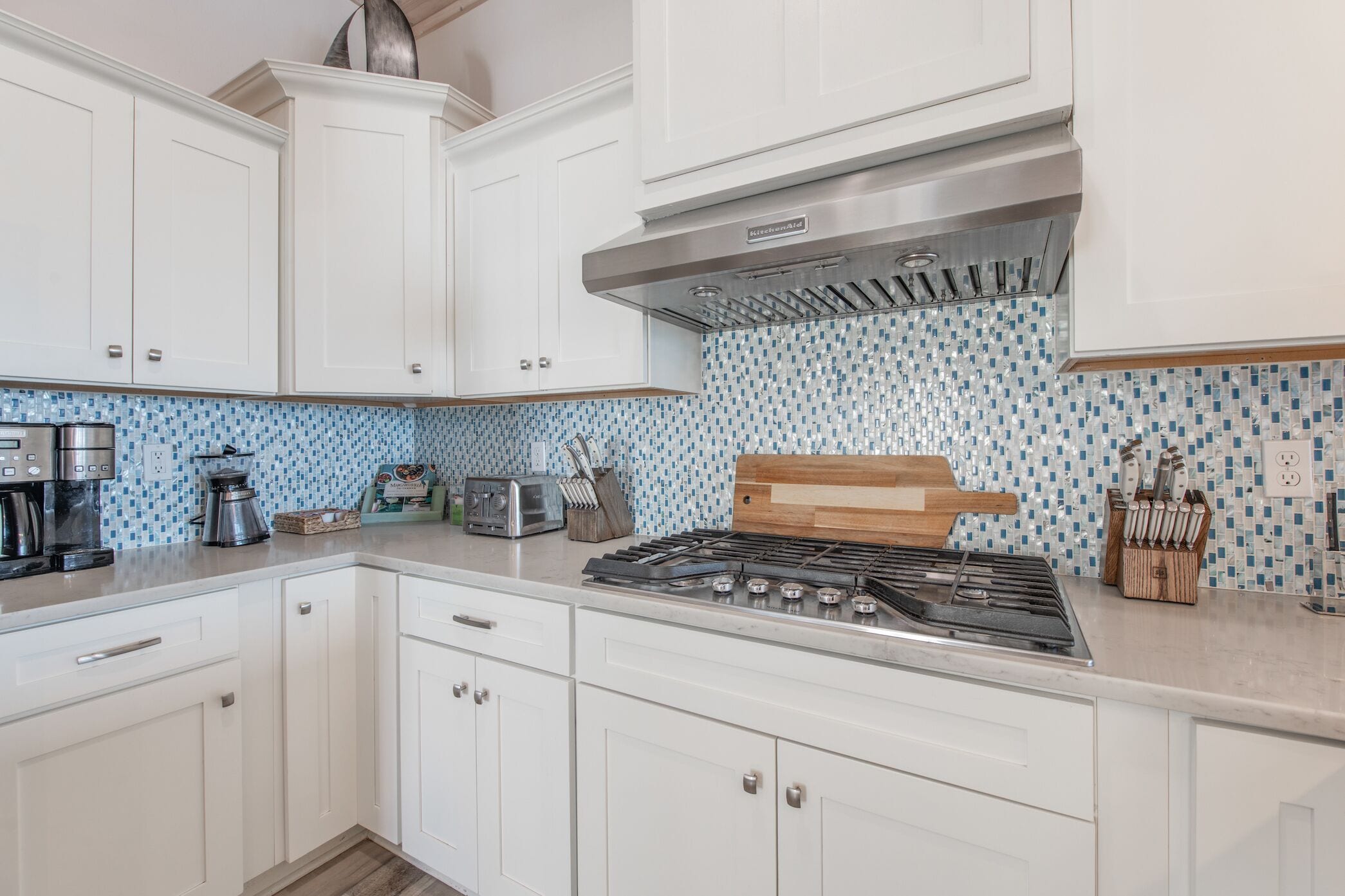 A kitchen with white cabinets, a gas stove, a coffee maker, and a toaster.