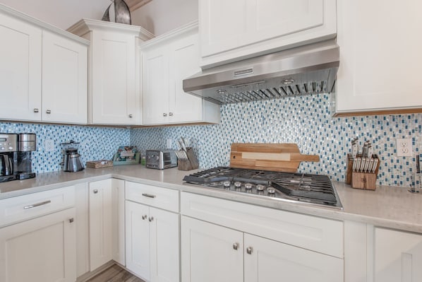 A kitchen with white cabinets, a gas stove, a coffee maker, and a toaster. - Waterfront Private Spa & elevator, Early Checkink (Port Aransas)