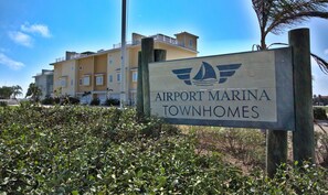 A sign for Airport Marina Townhomes with a view of multi-story buildings in the background. - Waterfront Luxury Private hot tub & elevator Slips (Port Aransas)