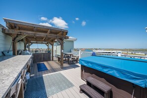 A wooden deck with a covered seating area, a pool, and a view of the beach and airport.