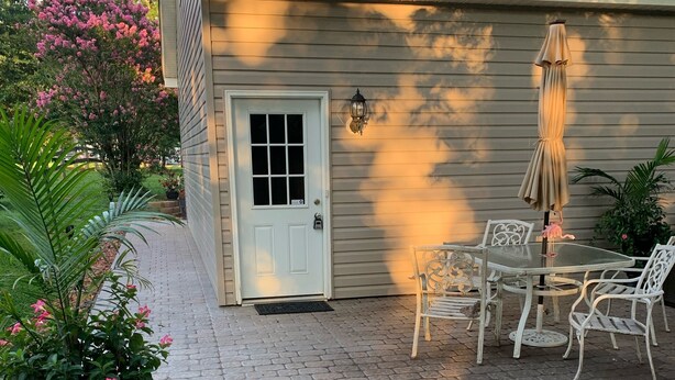 Une terrasse avec une porte blanche, des meubles d’extérieur et une plante en pot.