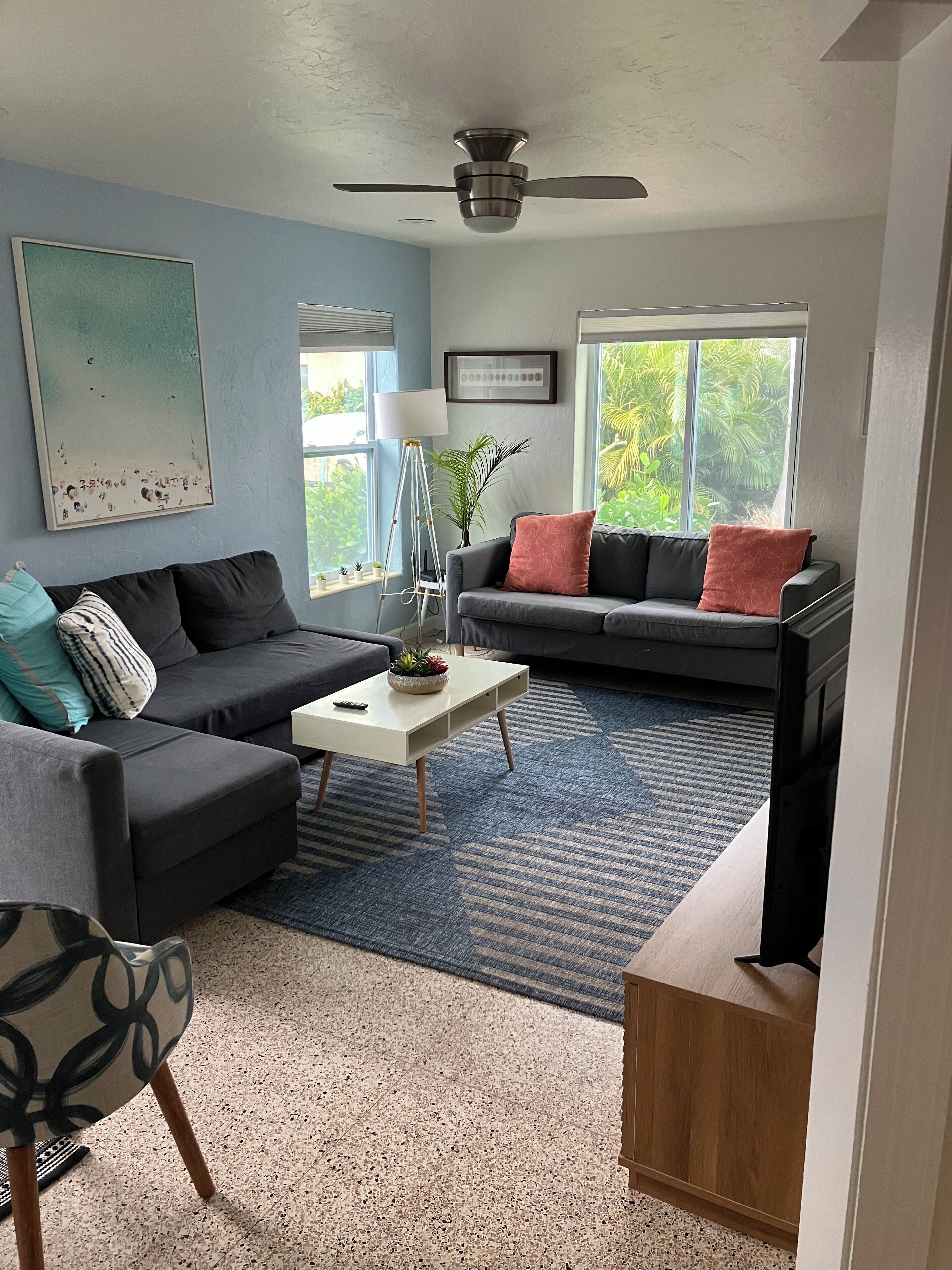 A living room with a gray sofa, a white coffee table, and a blue patterned rug.
