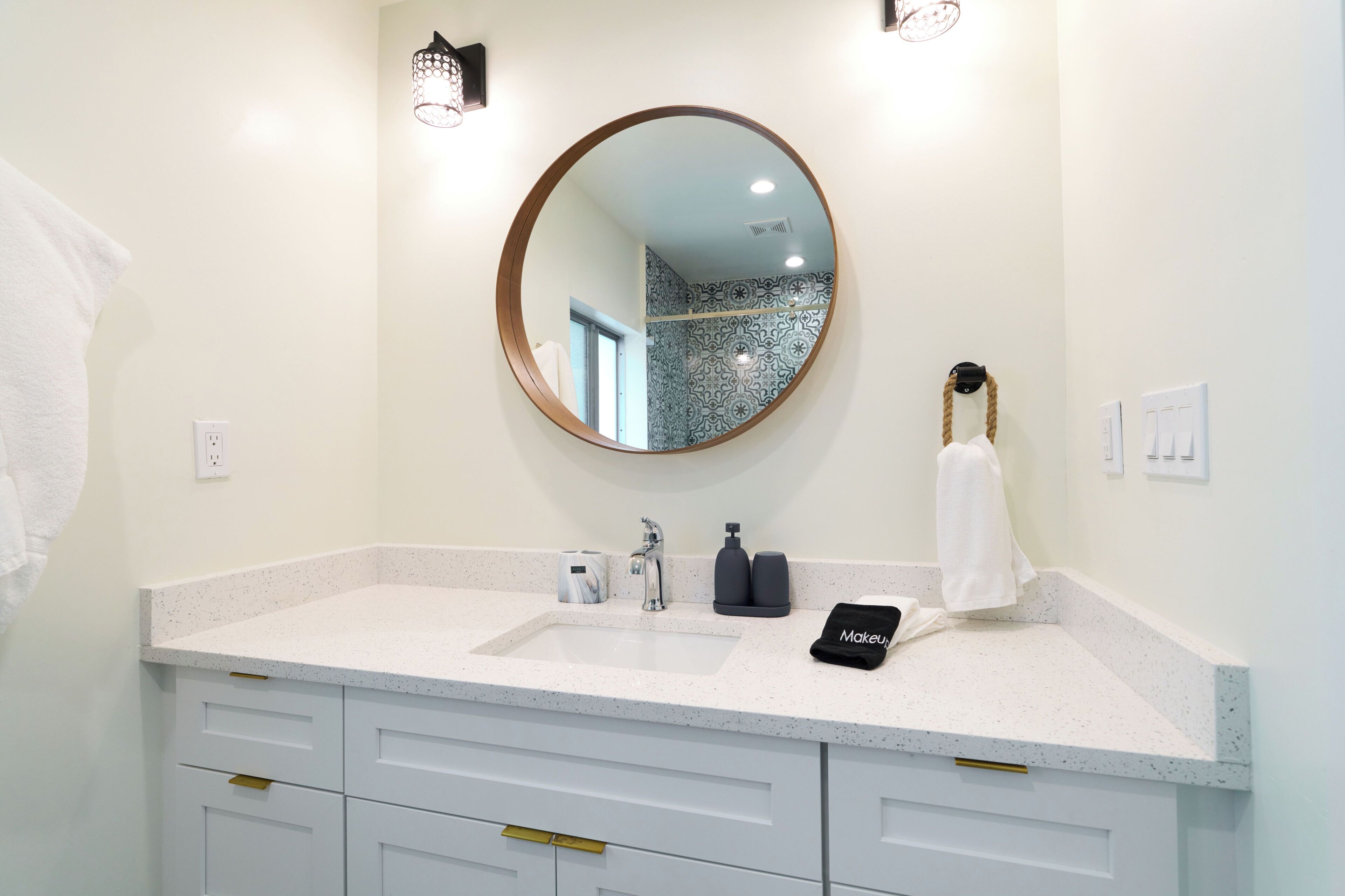 A bathroom with a round mirror, a sink, and a towel rack.