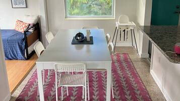 Una cocina moderna con armarios blancos, encimera de granito y comedor con mesa y sillas blancas.