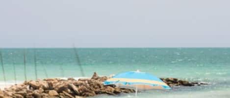 PĂ„ stranden, vit sandstrand, parasoller och strandhanddukar