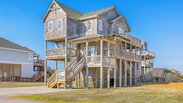 A multi-story wooden house with balconies and a staircase leading to the upper levels.