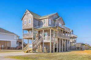 A multi-story wooden house with balconies and a staircase leading to the upper levels.