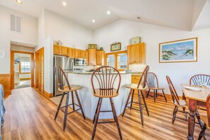 A spacious kitchen with wooden cabinets, a central island, and a dining area with wooden chairs.