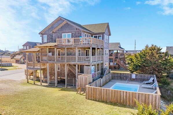 A multi-story wooden house with a balcony and a swimming pool.
