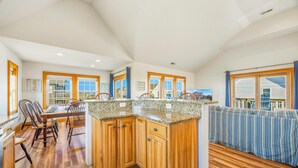 A spacious kitchen with wooden cabinets, granite countertops, and a dining area with chairs.