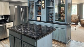 A kitchen with a marble countertop, built-in appliances, and a breakfast bar.