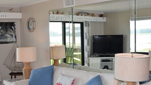A living room with a white sofa, blue cushions, a television, and a large window with a view of the sea. - Gorgeous 2 bed 2 bath beachfront condo (North Myrtle Beach)
