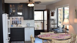 A kitchen with dark cabinets, a white refrigerator, a dining table with wooden chairs, and a view of the outside balcony. - Gorgeous 2 bed 2 bath beachfront condo (North Myrtle Beach)