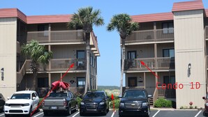 A parking lot with a row of vehicles parked in front of a building with balconies and palm trees. - Gorgeous 2 bed 2 bath beachfront condo (North Myrtle Beach)