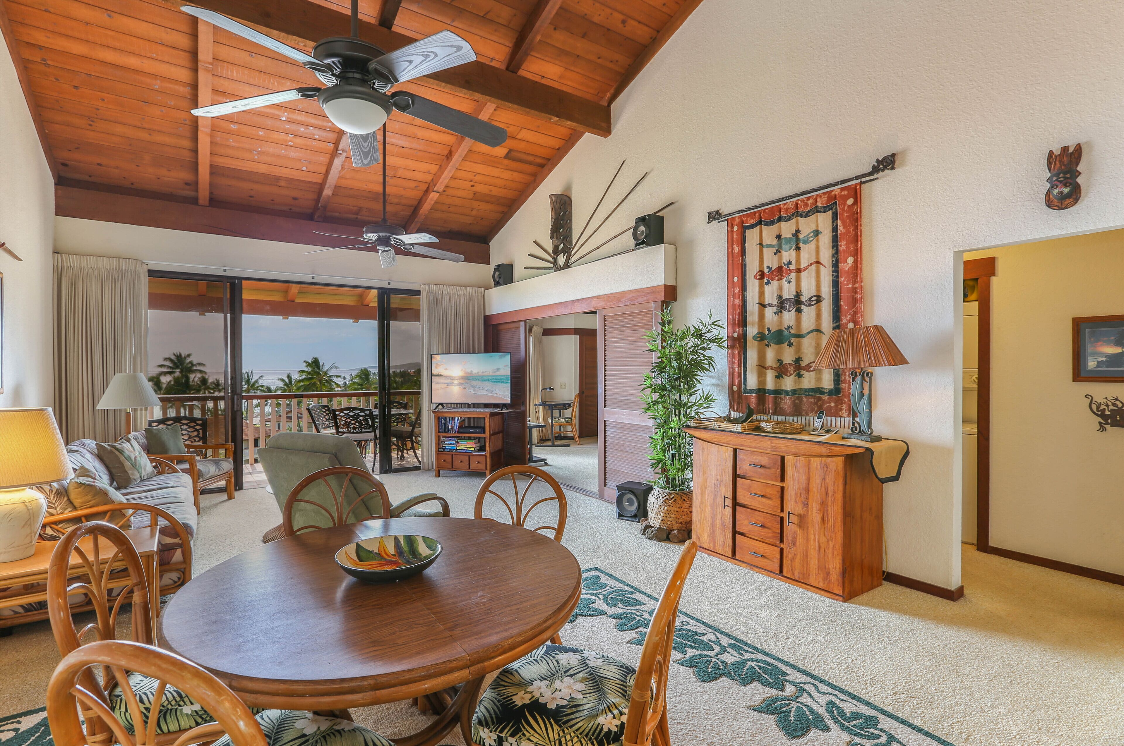 A spacious living room with a wooden ceiling, a dining table, and a TV.