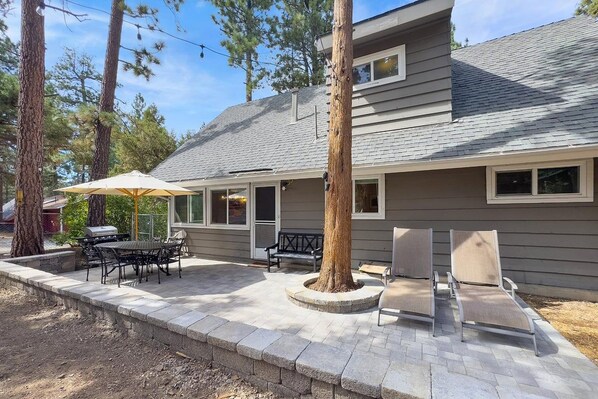 A house with a patio, outdoor furniture, and a tree.