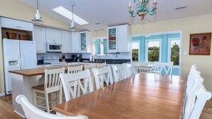 Una cocina amplia con armarios blancos, una mesa de comedor de madera y un candelabro.